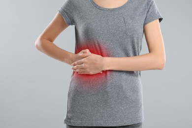 Woman suffering from liver pain on grey background, closeup