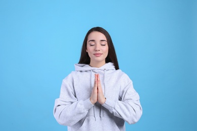 Young woman meditating on light blue background. Stress relief exercise