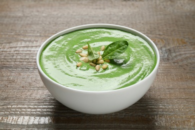 Photo of Bowl of healthy green soup with fresh spinach on wooden table