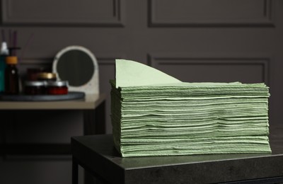 Photo of Stack of green paper napkins on grey table indoors. Space for text
