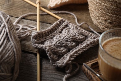 Photo of Soft grey woolen yarn, knitting and needles on wooden table, closeup