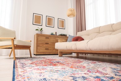 Photo of Beautiful rug, sofa, armchair and chest of drawers indoors, low angle view