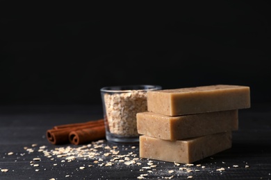 Photo of Handmade soap bars, oatmeal and cinnamon sticks on table