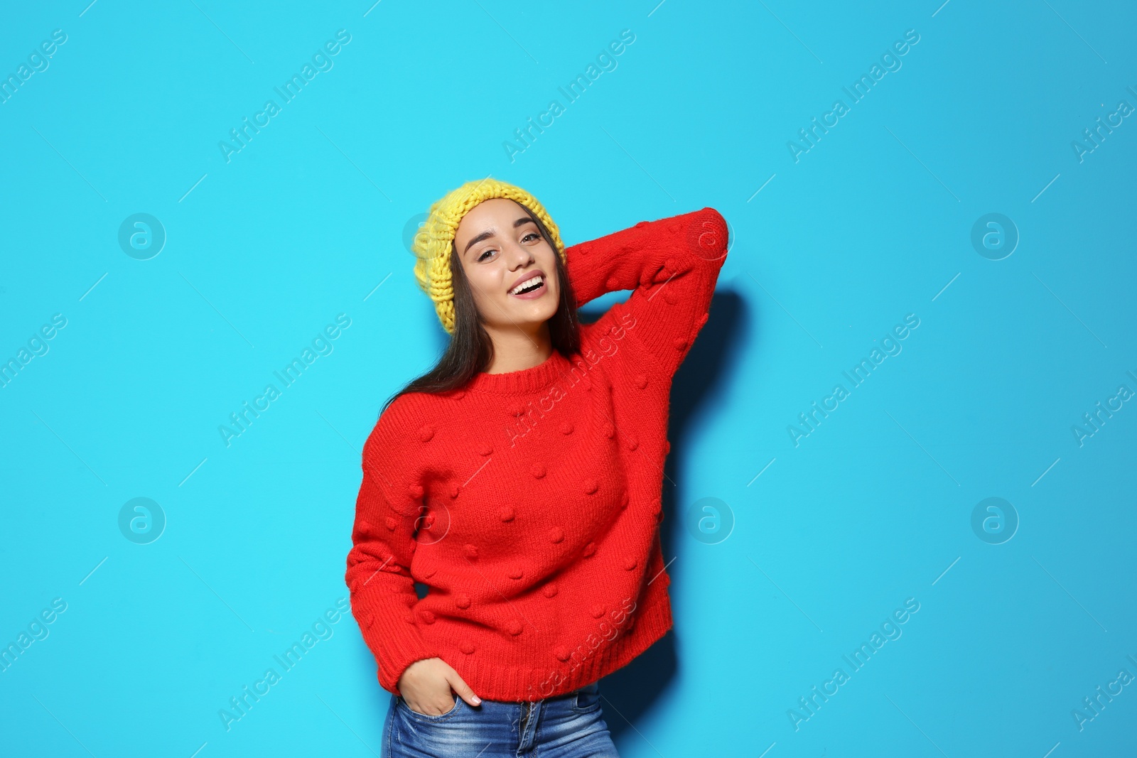 Photo of Young woman in warm sweater and hat on color background. Celebrating Christmas