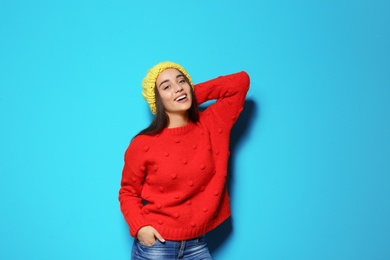 Photo of Young woman in warm sweater and hat on color background. Celebrating Christmas