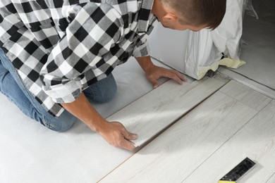 Professional worker installing new laminate flooring indoors, closeup