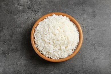 Photo of Bowl of tasty cooked rice on grey background, top view