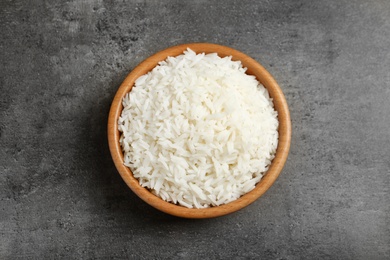 Bowl of tasty cooked rice on grey background, top view