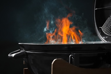 Photo of New modern barbecue grill with fire on dark background