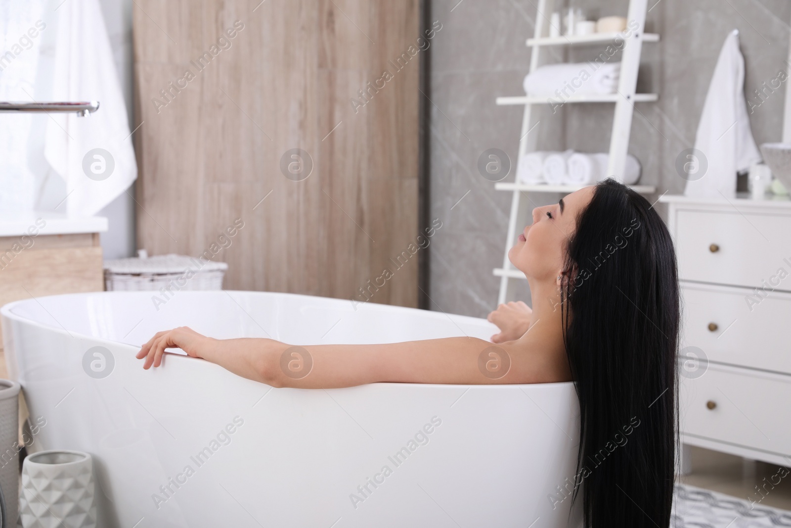 Photo of Beautiful young woman relaxing in bathtub at home