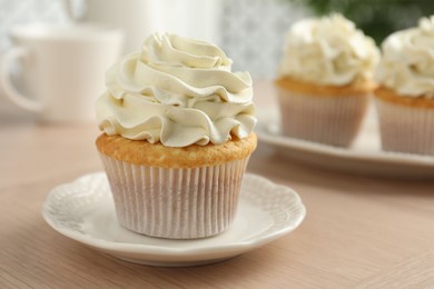 Photo of Tasty cupcake with vanilla cream on light wooden table, closeup