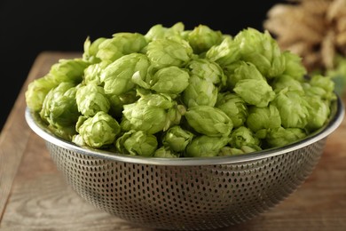 Photo of Fresh green hops in sieve on table, closeup