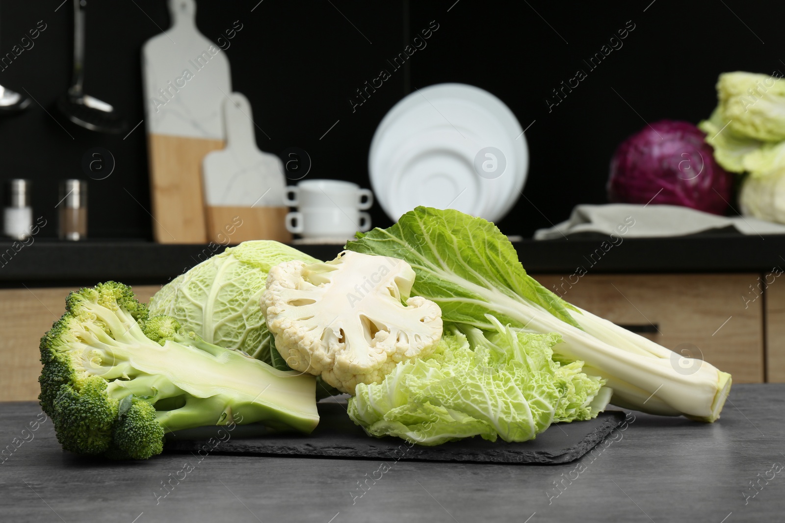 Photo of Different types of cut cabbage on grey table in kitchen