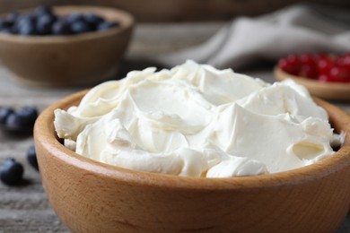 Photo of Tasty cream cheese in wooden bowl, closeup