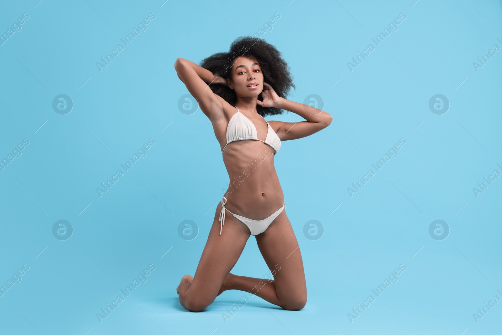 Photo of Beautiful woman in stylish bikini posing on light blue background