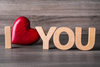Photo of Phrase I Love You made of decorative heart and letters on wooden table, closeup