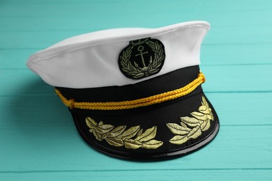 Photo of Peaked cap with accessories on turquoise wooden background