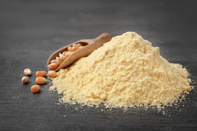 Photo of Pile of corn flour and scoop with kernels on table