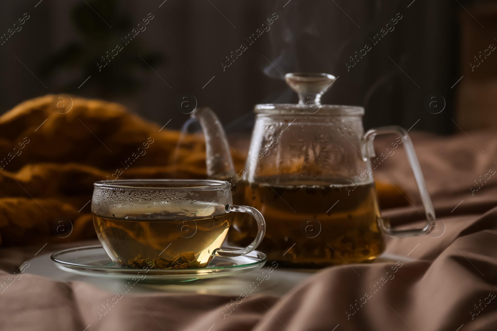 Photo of Tray with cup of hot tea and teapot on bed