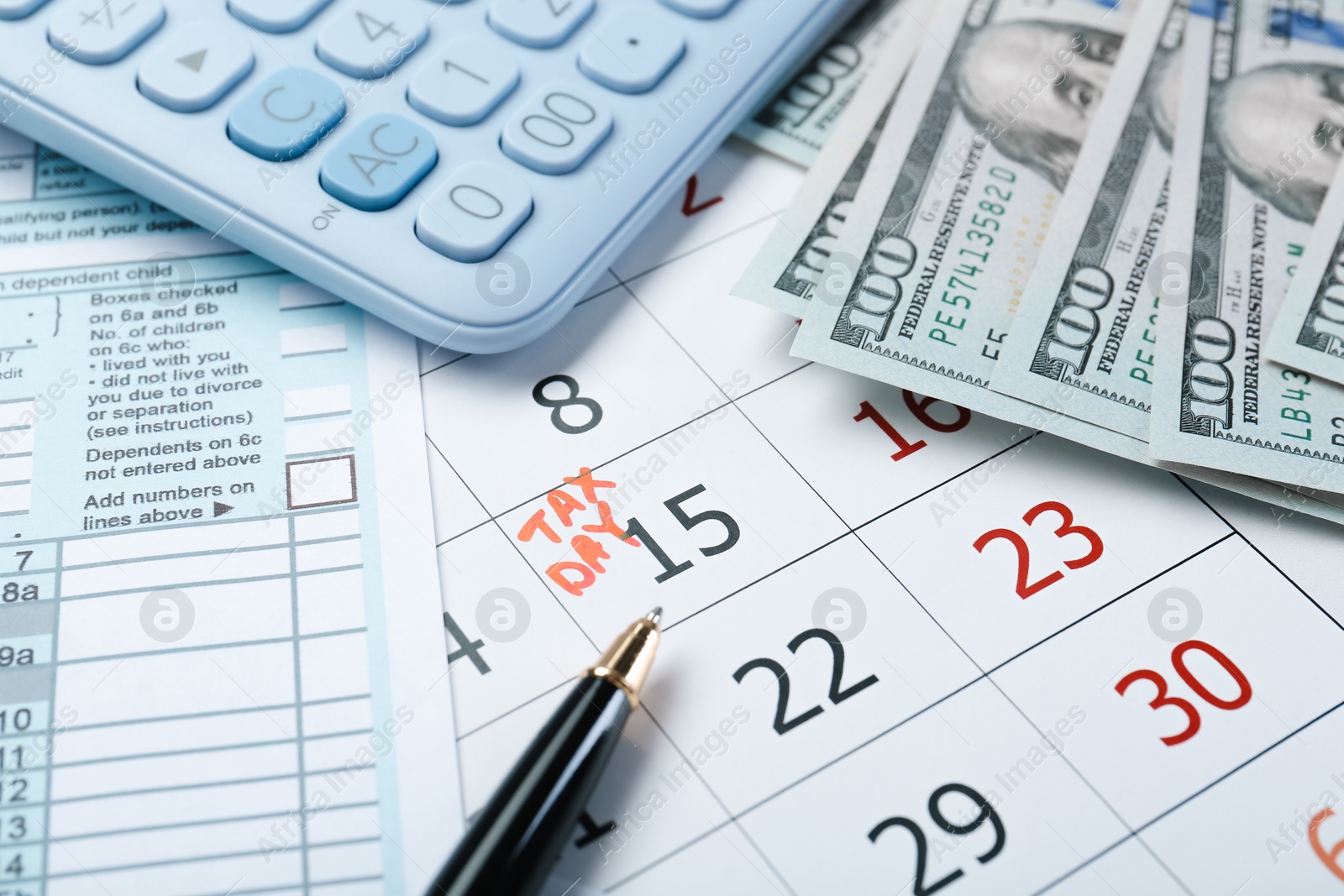 Photo of Calendar with date reminder about tax day, documents, money, pen and calculator, closeup