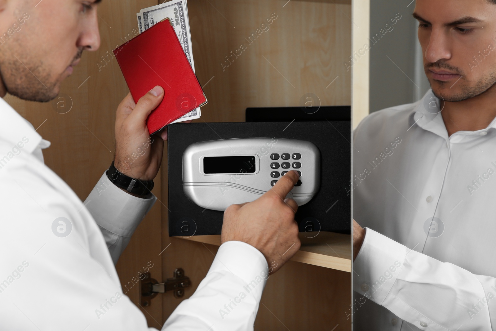 Photo of Man opening black steel safe with electronic lock at hotel, closeup