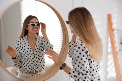 Photo of Young woman getting ready near mirror at home. Morning routine