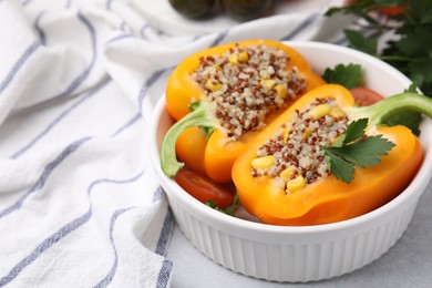 Photo of Quinoa stuffed bell pepper and parsley in bowl on light table, closeup. Space for text