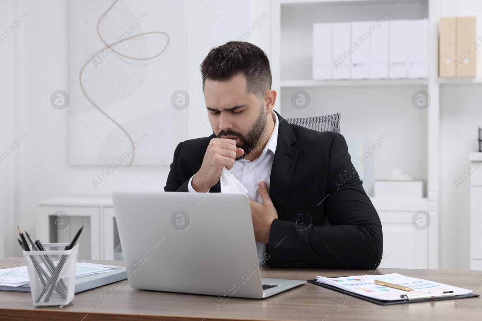 Photo of Sick man coughing at workplace in office