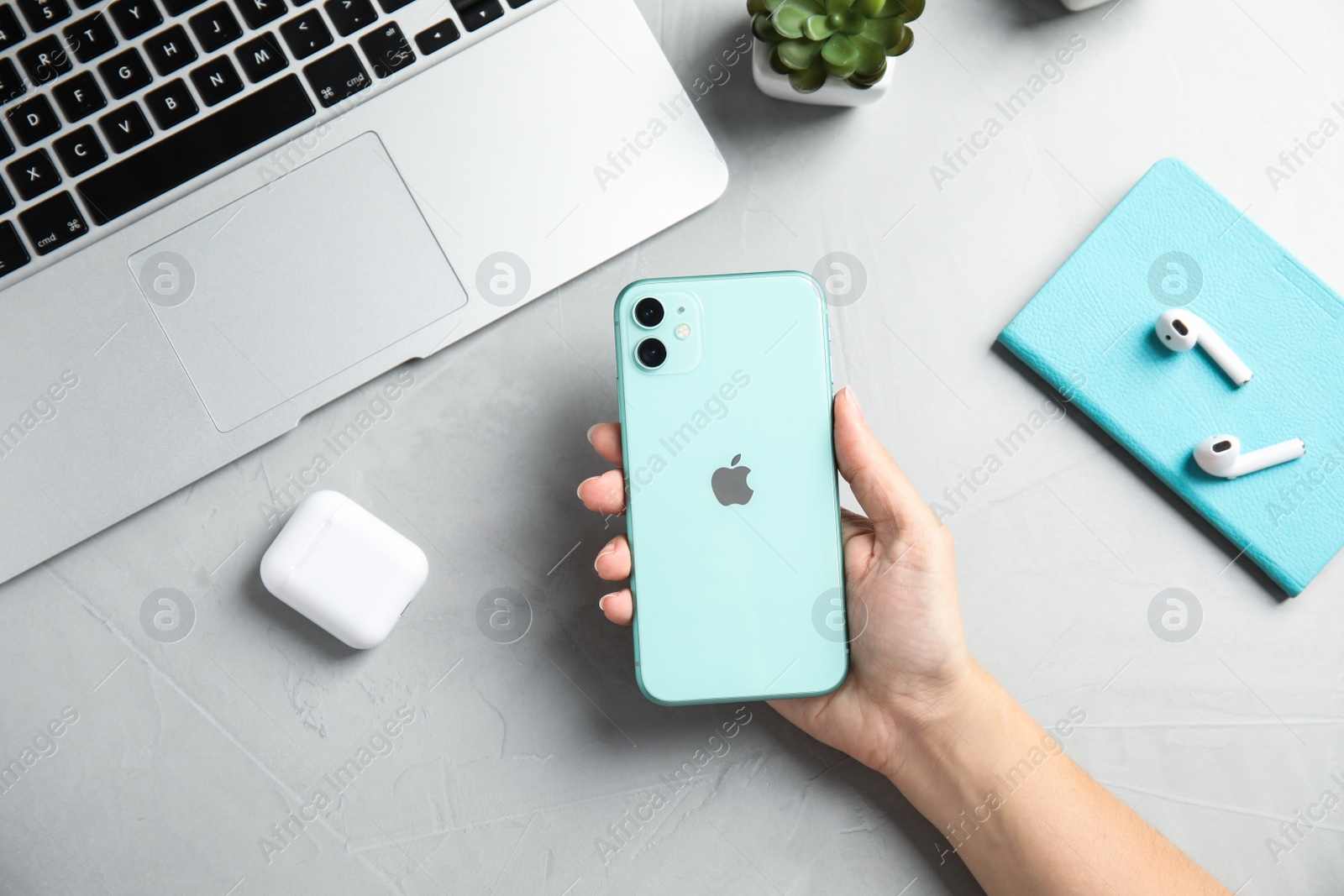 Photo of MYKOLAIV, UKRAINE - JULY 10, 2020: Woman holding Iphone 11 Green at table, top view