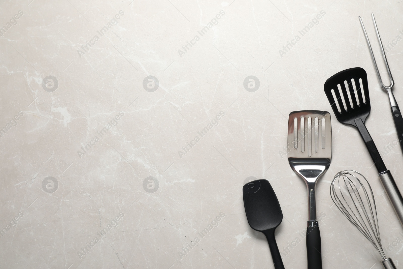 Photo of Different spatulas, whisk and carving fork on light marble table, flat lay. Space for text