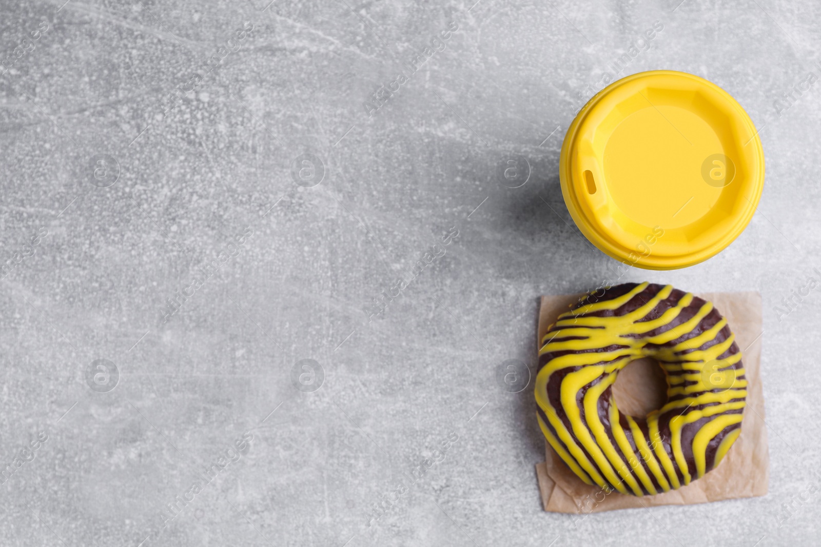 Photo of Tasty frosted donut and hot drink on light grey table, flat lay. Space for text