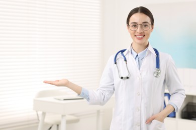 Medical consultant with glasses and stethoscope in clinic, space for text