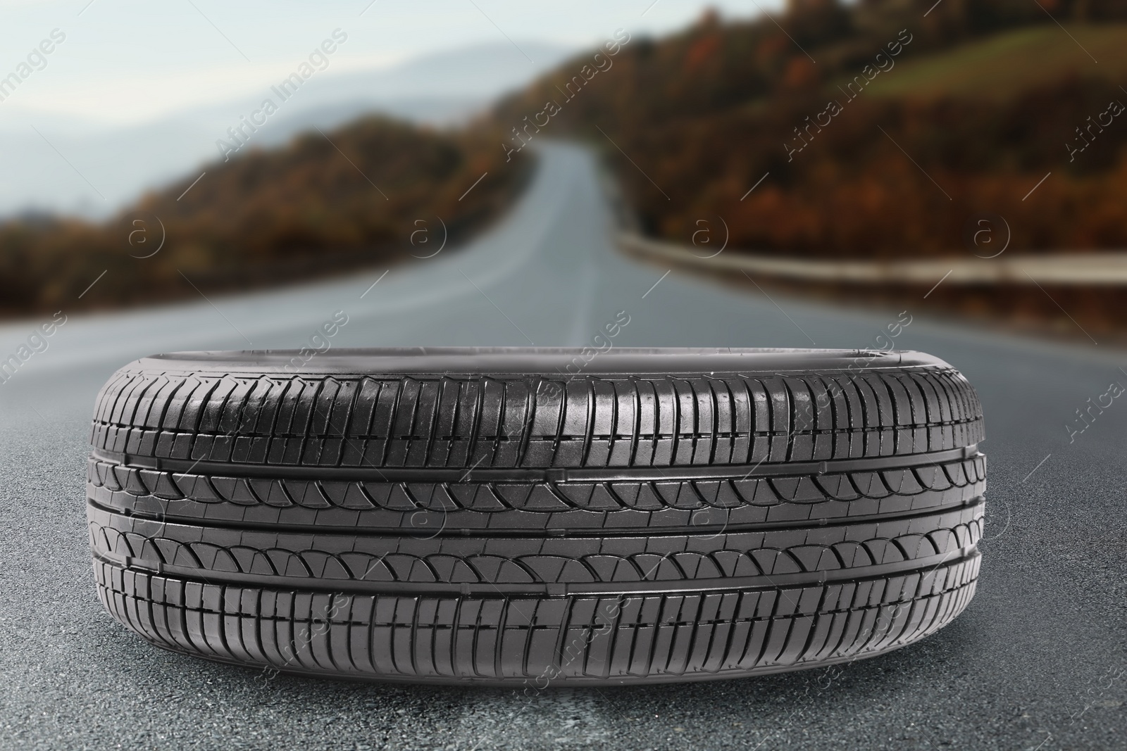 Image of Black car tire on asphalt highway outdoors, closeup