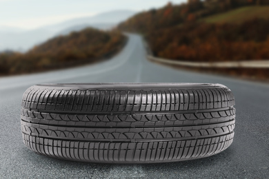 Image of Black car tire on asphalt highway outdoors, closeup