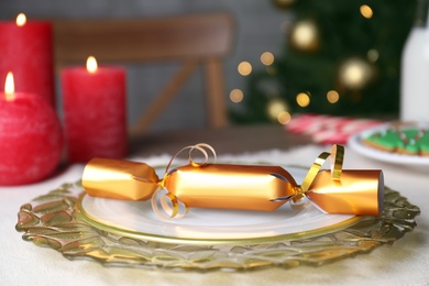 Photo of Plate with Golden Christmas cracker on table, closeup
