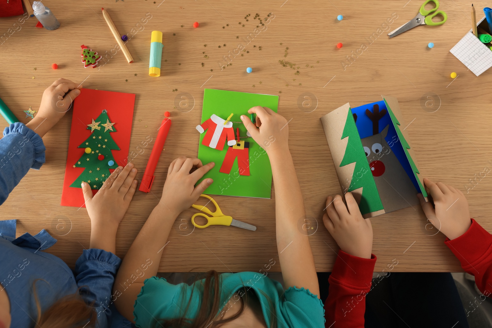 Photo of Little children making beautiful Christmas greeting cards at table, top view