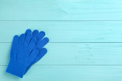 Stylish blue gloves on turquoise wooden background, flat lay. Space for text