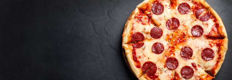 Image of Top view of hot delicious pizza on dark table, space for text. Banner design 