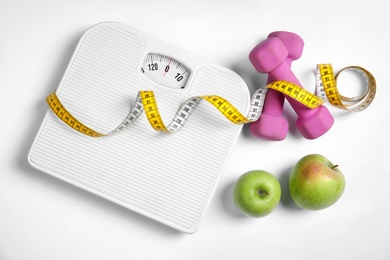 Photo of Composition with scales, apples, tape measure and dumbbells on white background, top view
