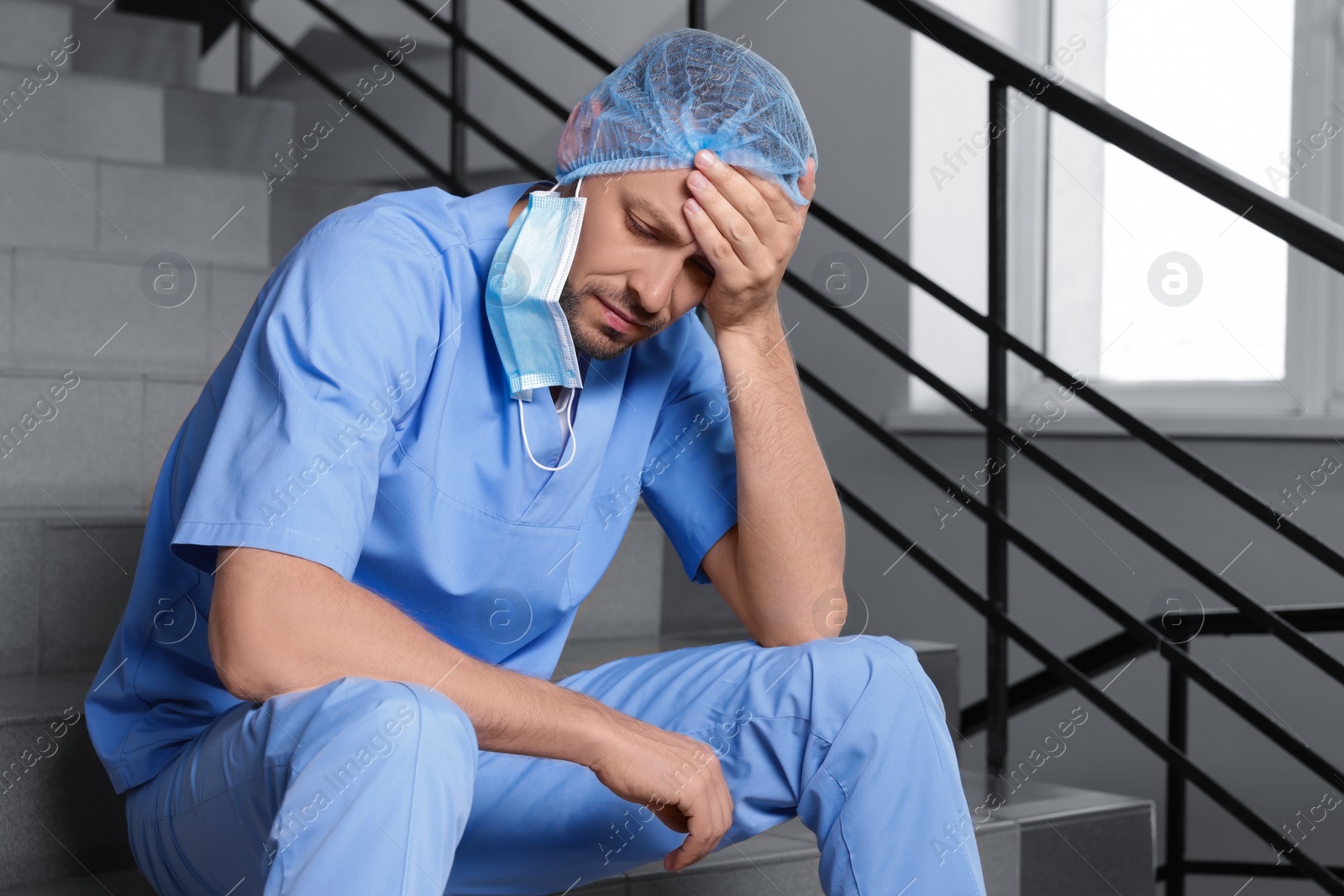 Photo of Exhausted doctor sitting on stairs in hospital