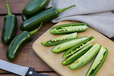 Photo of Fresh green jalapeno peppers on wooden table, closeup