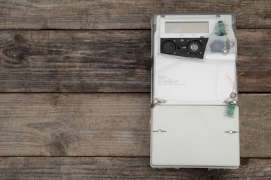 Photo of Electric meter on wooden background, top view with space for text. Measuring device