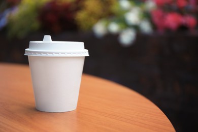 Cardboard cup with tasty coffee on table outdoors