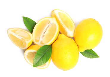 Photo of Cut and whole ripe lemons with green leaves on white background, top view