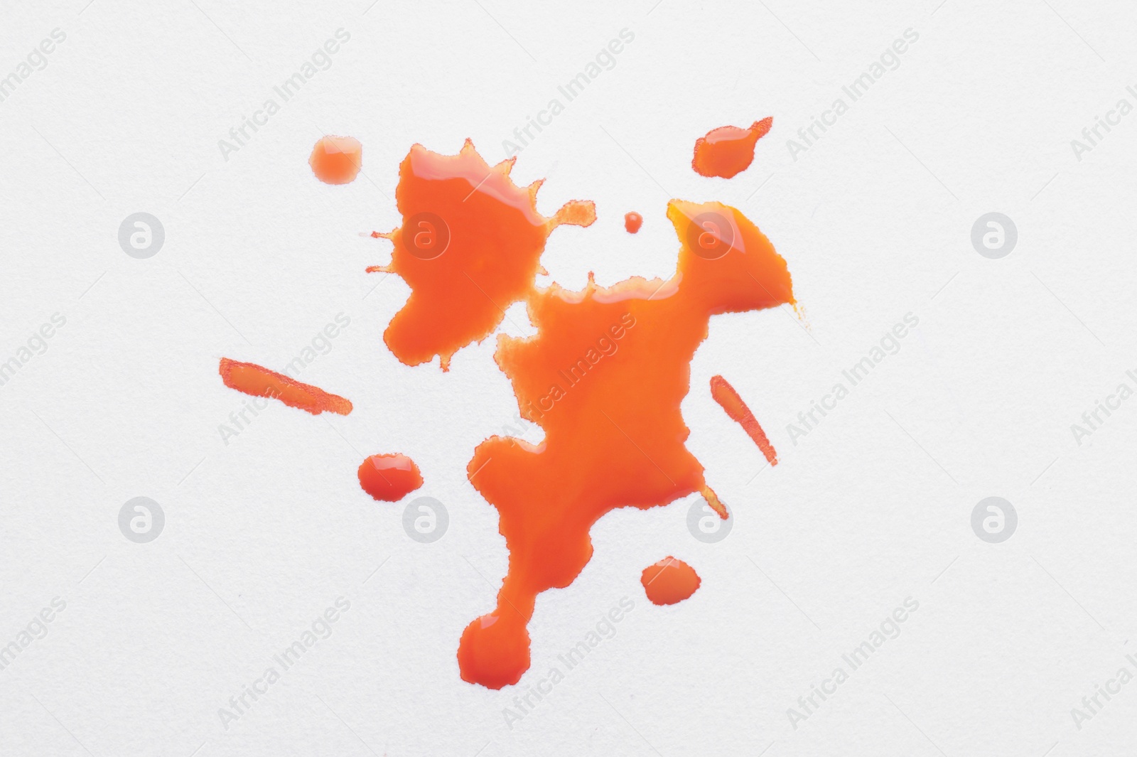 Photo of Blot of orange ink on white background, top view