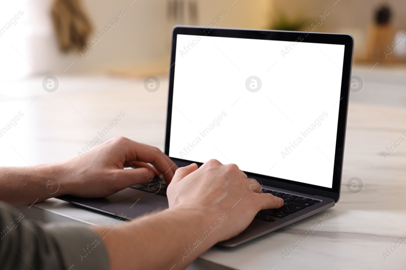 Photo of Man working on laptop at white marble table indoors, closeup