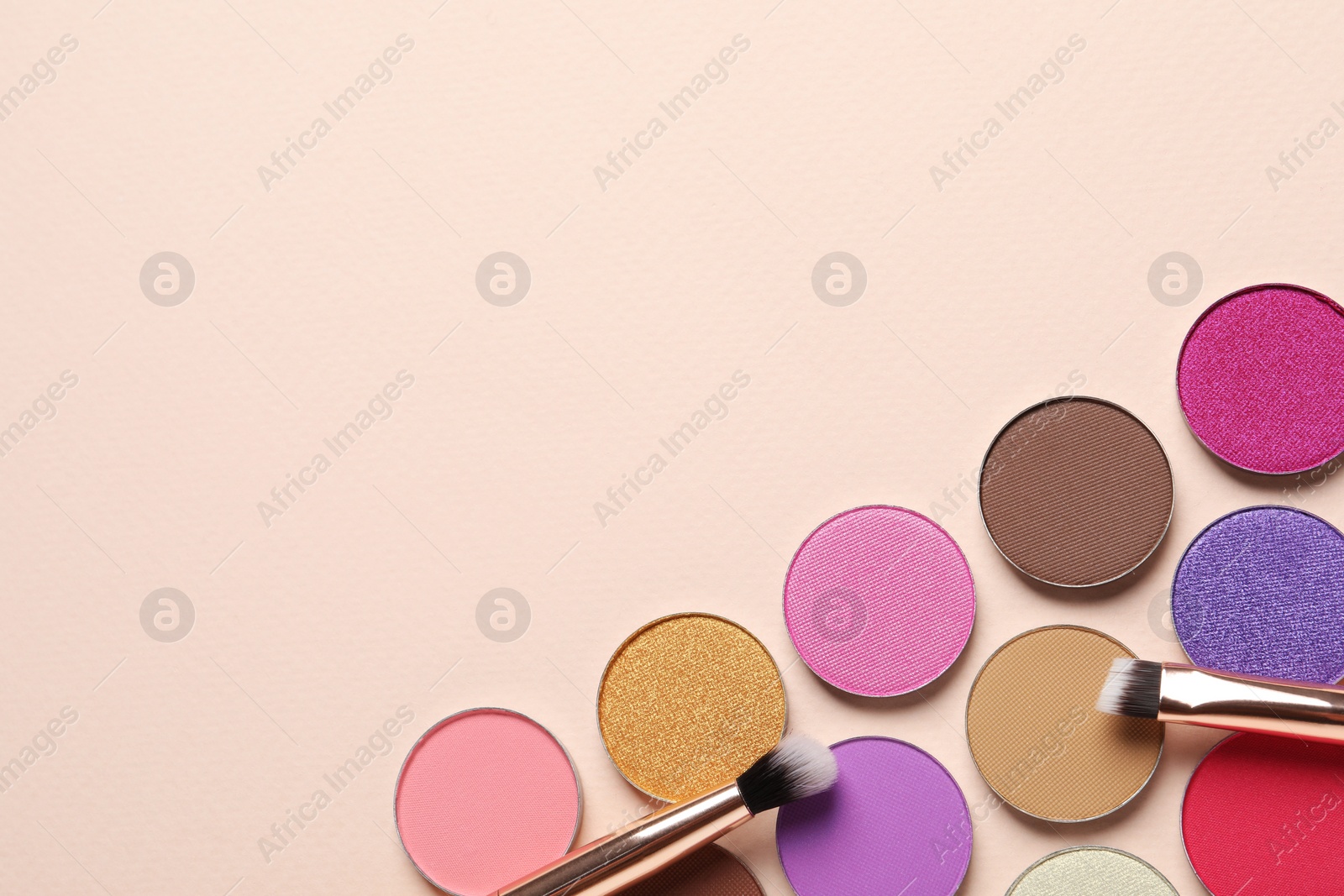 Photo of Different beautiful eye shadows and makeup brushes on beige background, flat lay. Space for text