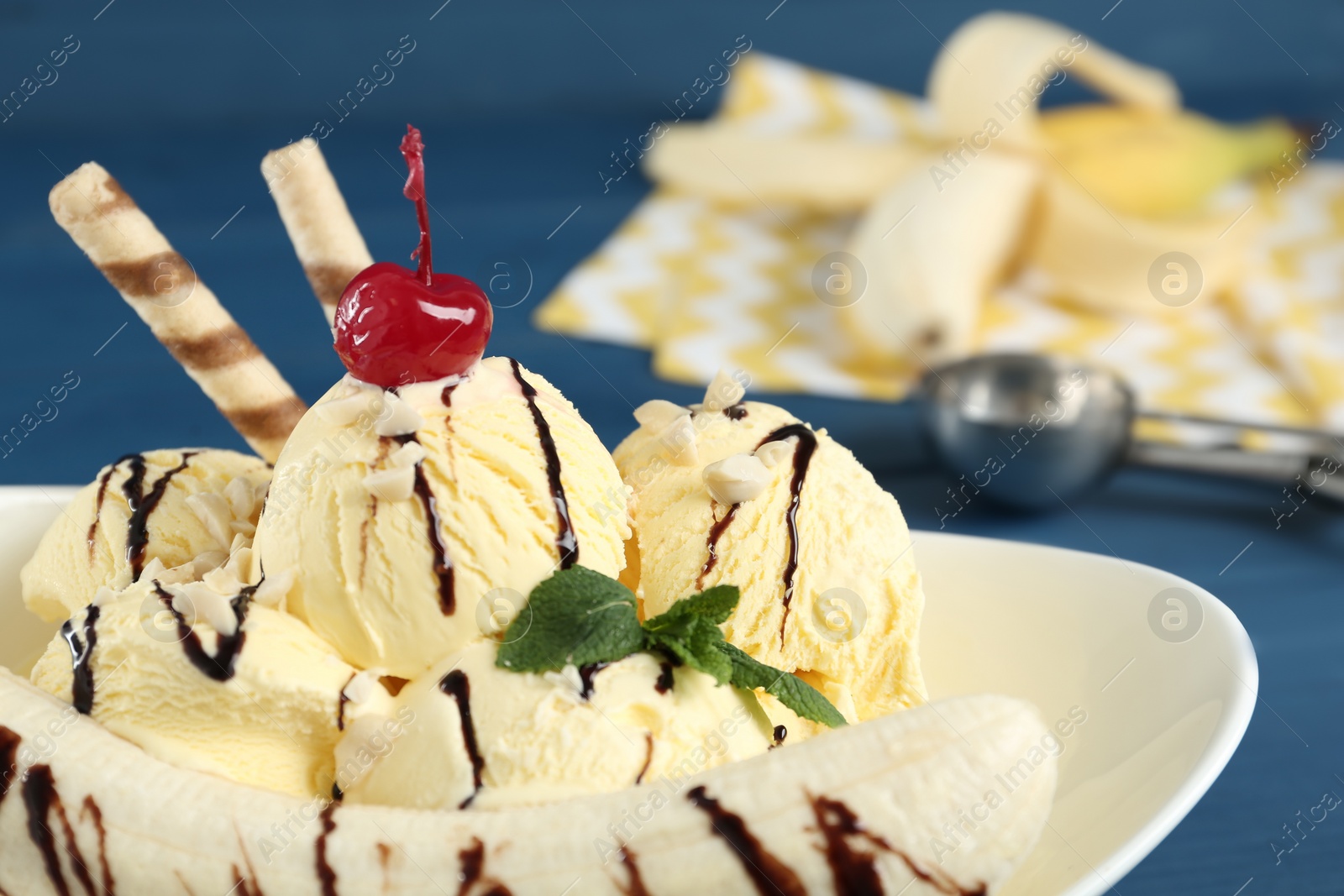 Photo of Delicious dessert with banana ice cream on blue table, closeup