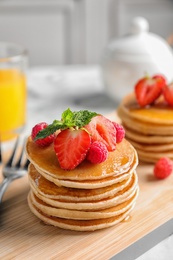 Tasty pancakes with berries on wooden board