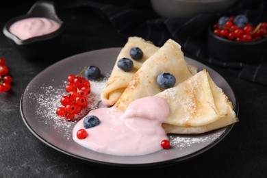 Photo of Delicious crepes with natural yogurt, blueberries and red currants on dark grey table